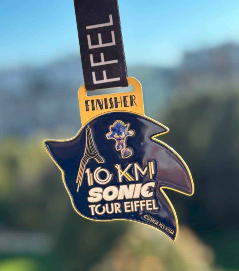 Une médaille en forme de tête de Sonic avec écrit "10km Sonic Tour Eiffel"